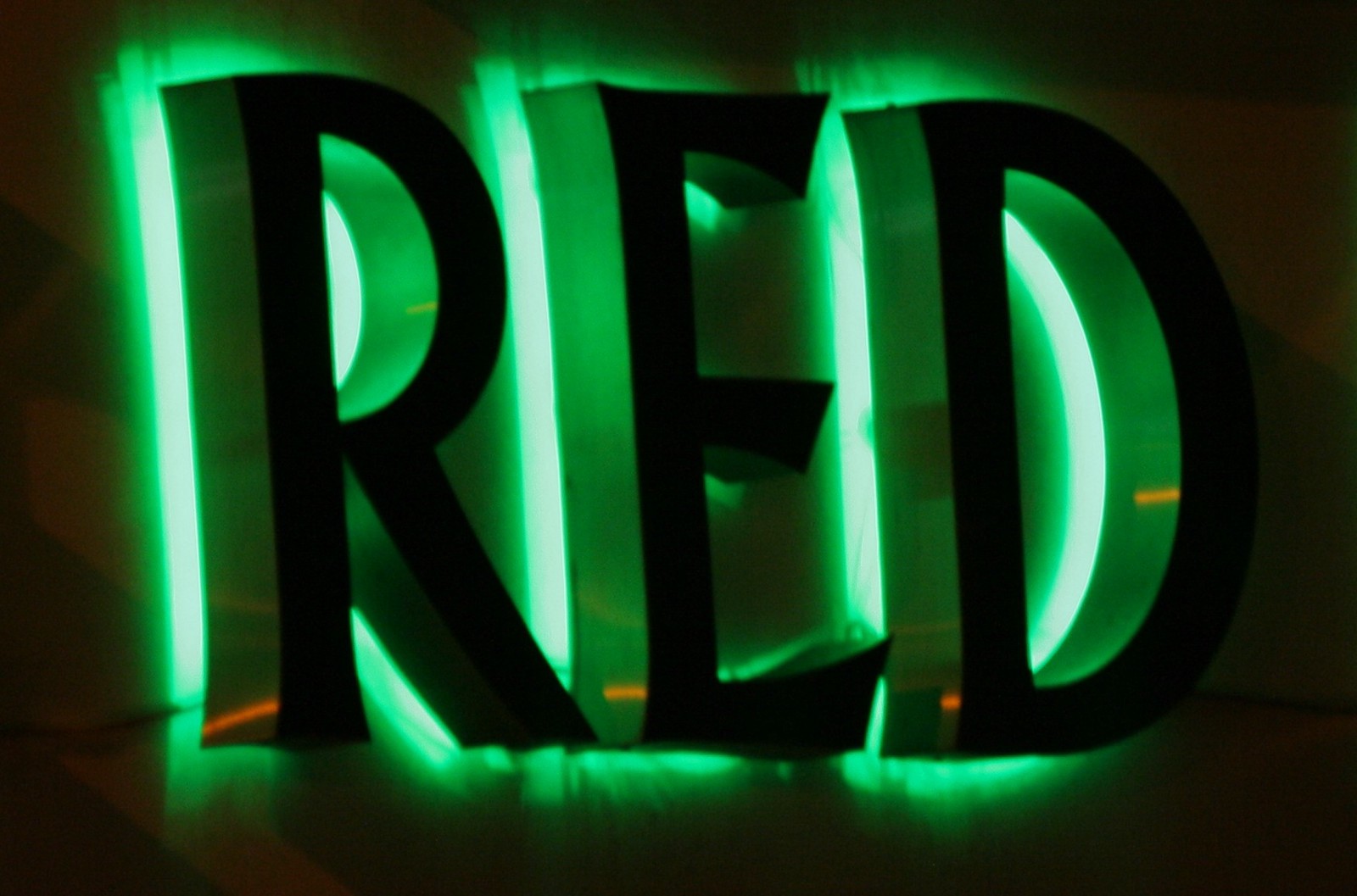 Foto da palavra red em destaque e luz neon verde no contorno de cada letra.