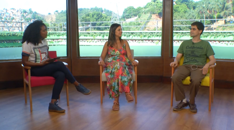 Três pessoas sentadas lado a lado em cadeiras separadas. Da esquerda para a direita, Karen de Souza, Simone Freire e Marcos Silva. Ambas olham para o lado direito, em direção ao Marcos.