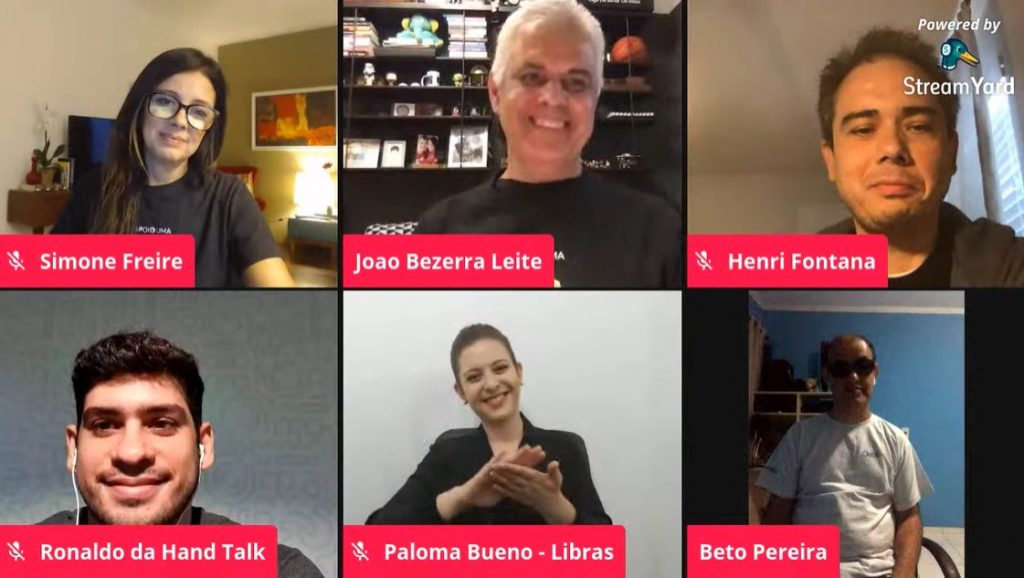 Captura de tela da transmissão da live exibe os rostos dos seis convidados, separados em pequenos retângulos dispostos lado a lado. Da esquerda para a direita: Simone Freire, João Bezerra Leite, Henri Fontana, Ronaldo Tenório, Paloma Bueno (intérprete de Libras) e Beto Pereira.