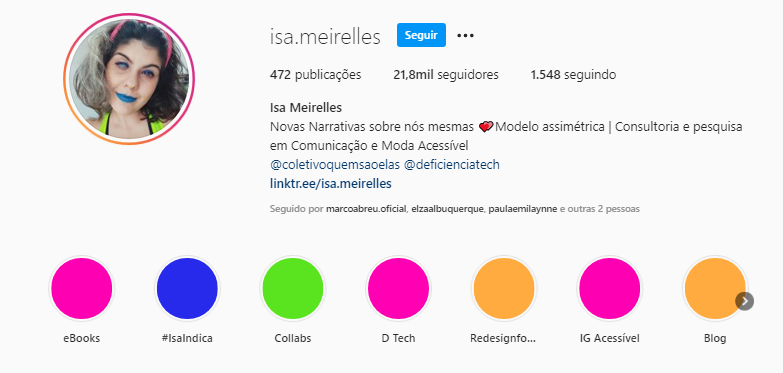 Reprodução da área inicial do Instagram da Isa com elementos coloridos nos destaques e a foto dela no canto superior esquerdo. Ela tem cabelos ondulados nas cores preta e branca, usa uma blusa verde e batom azul.