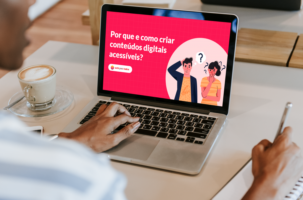 Foto de um notebook sobre uma mesa e na tela está projetada a capa do e-book "Por que e como criar conteúdos digitais acessíveis?"