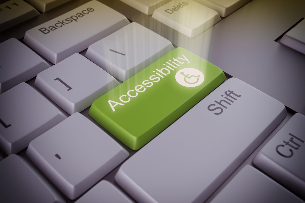 Foto de parte do teclado de um computador com a tecla "acessibilidade" destacada em verde entre as outras em branco.